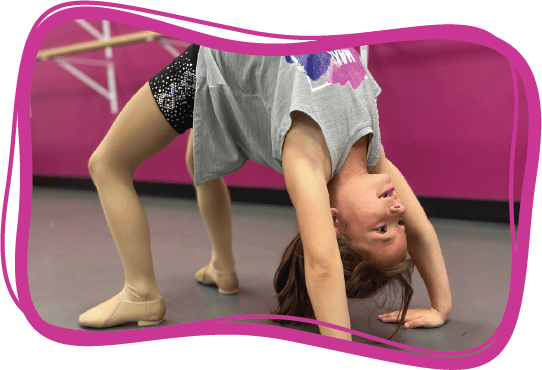 A young girl is excited as she completes a back bend with her hands and feet entirely on the ground.